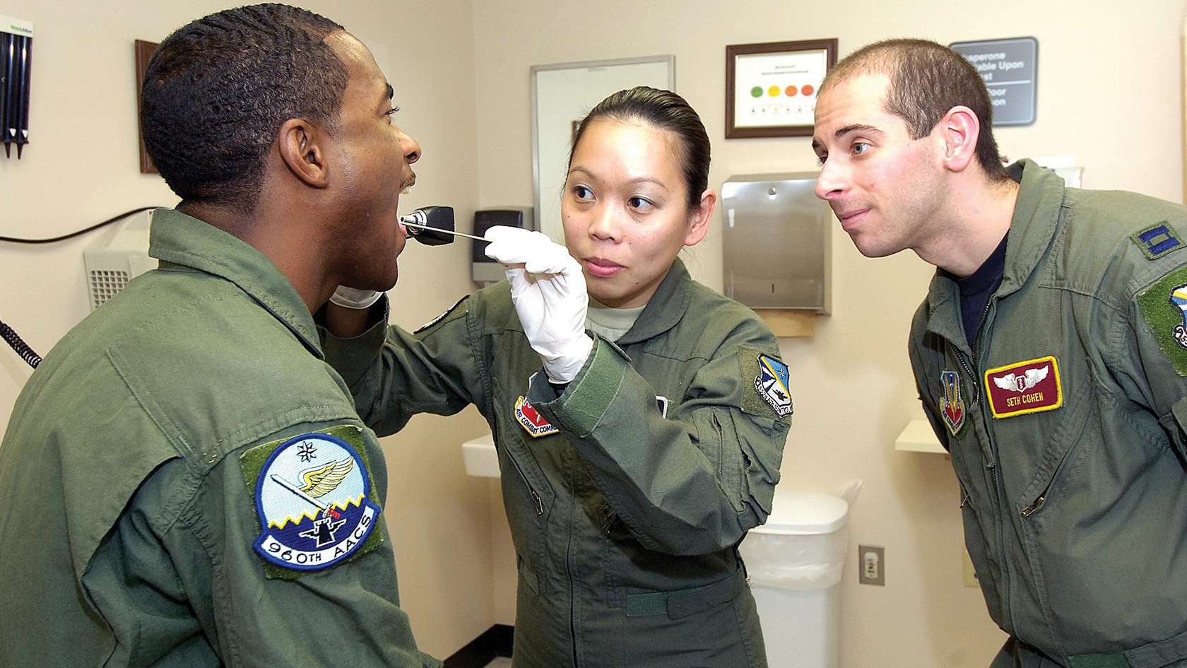 Air Force flight surgeon providing an exam to two Airmen