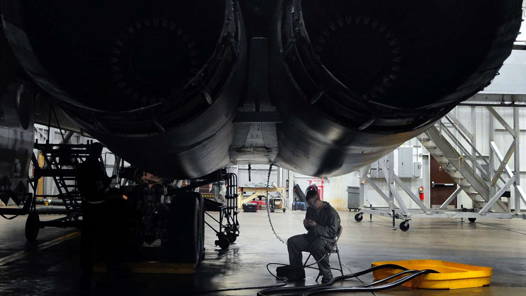 airman performing maintenance under an aircraft