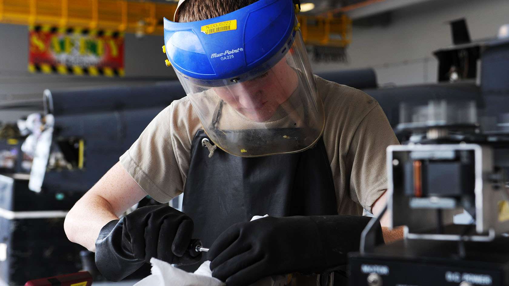 airman with face shield repairing aircraft part