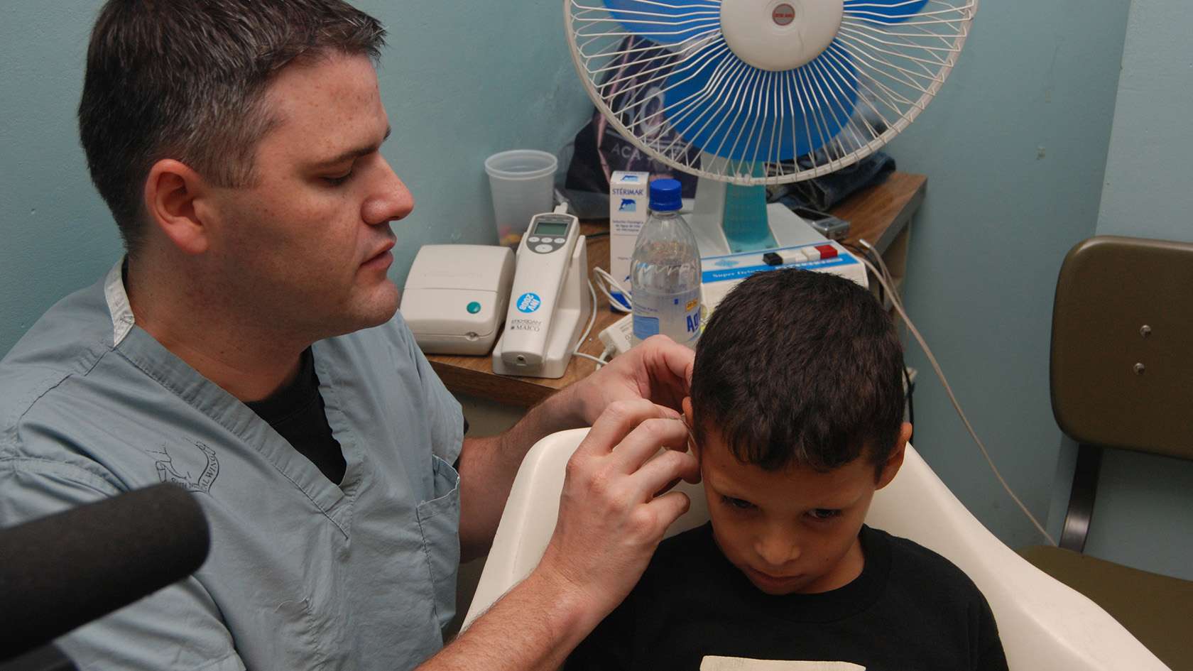 audiologist helping little boy set up for audio exam