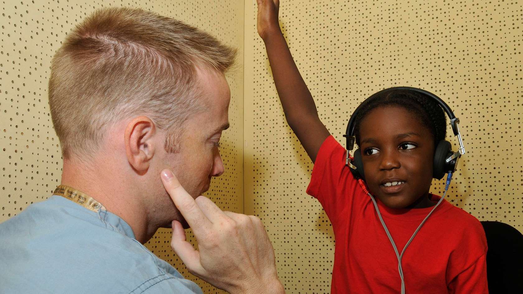 audiologist helping little boy with audio exam
