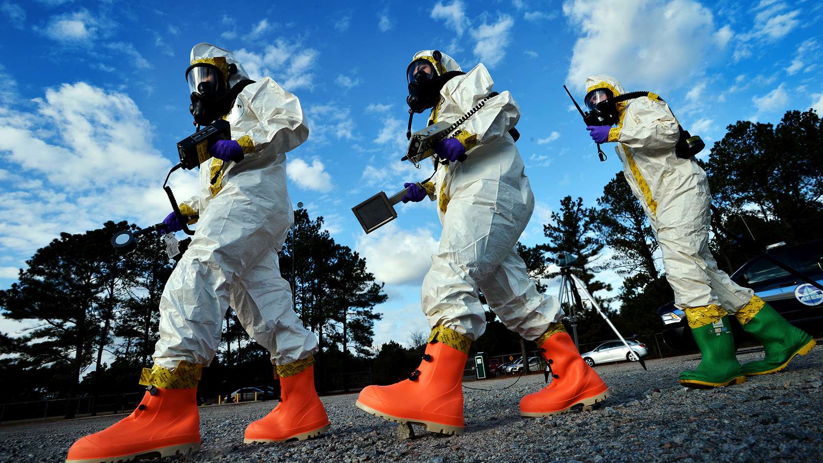 three biomedical engineers walking while wearing full-body protective gear