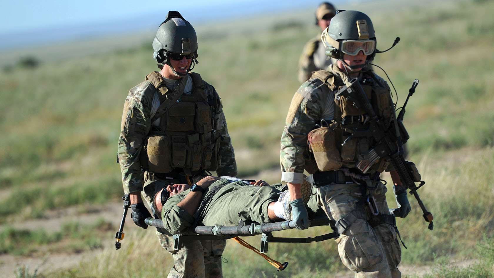 Two Combat Rescue Officers transporting an Airman on a gurney