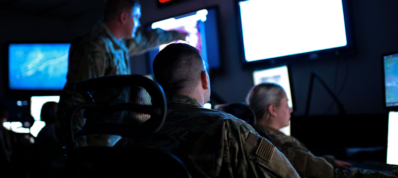 ALL SOURCE INTELLIGENCE ANALYSTS LOOKING AT SEVERAL MONITORS