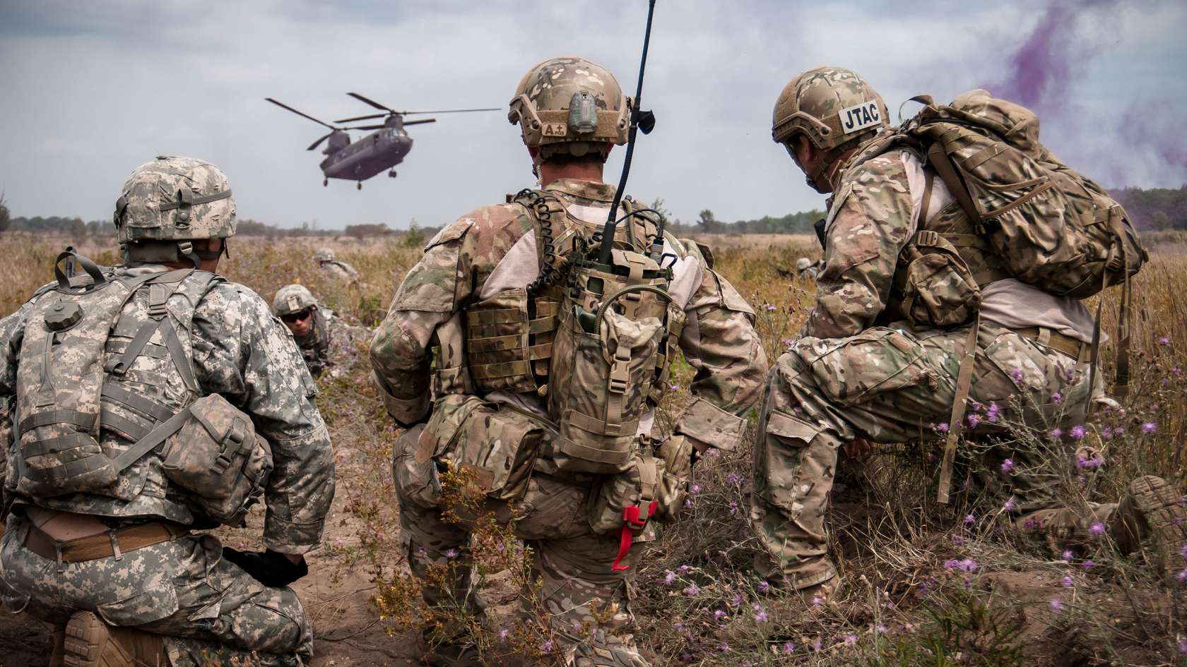 Group of three TACP officers in the field looking at a helicopter