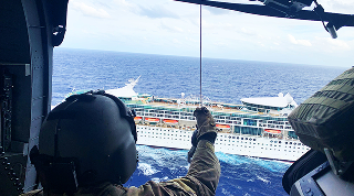 soldier in a helicopter looking at a cruise ship from the air