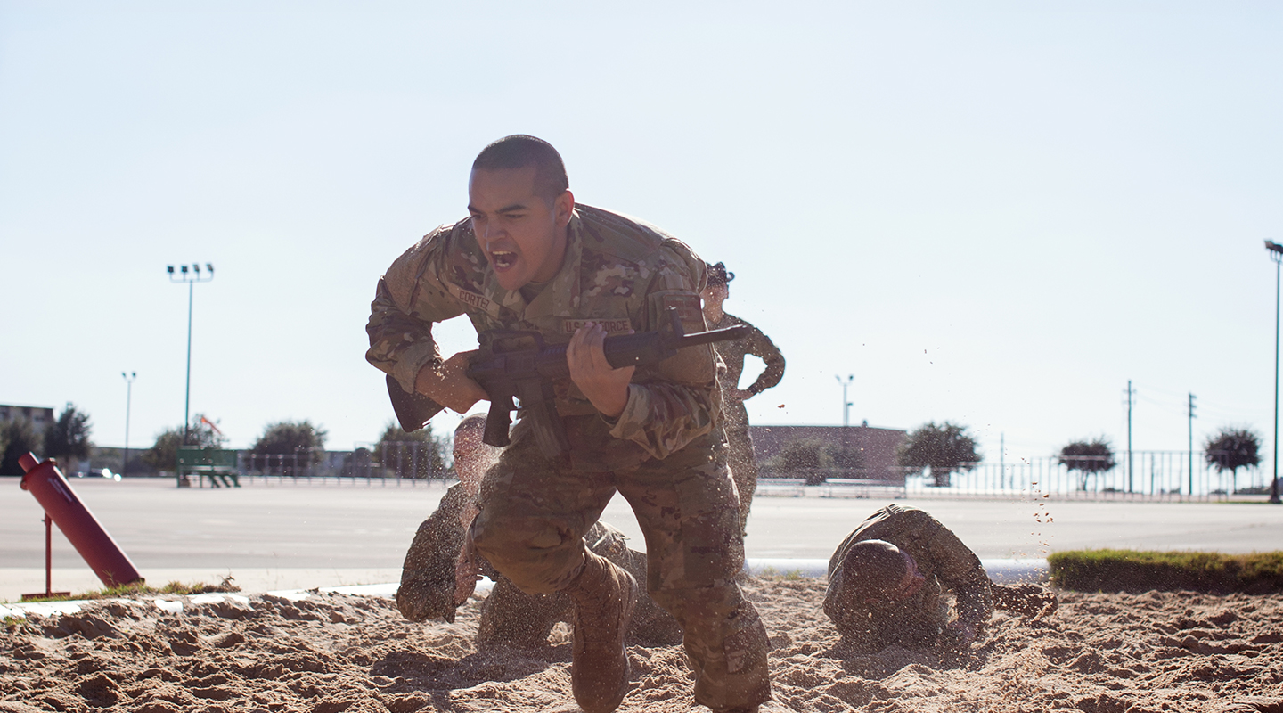 trainee running on sand carrying a weapon