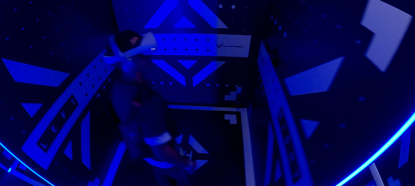 A person in a VR headset stands in a dark, blue-lit room with geometric patterns, evoking the Air Force's precision and advanced flight technology..