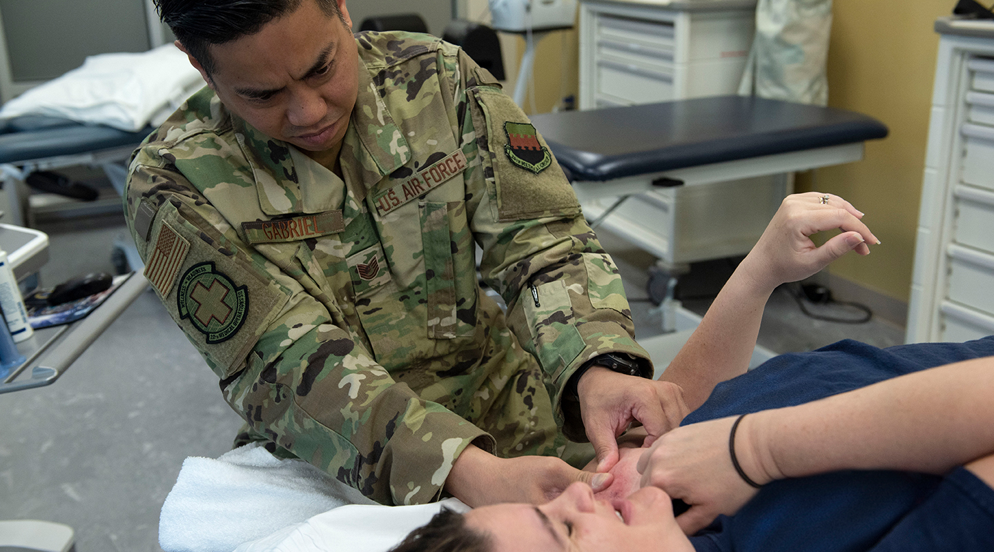airman in uniform helping a patient with his shoulder