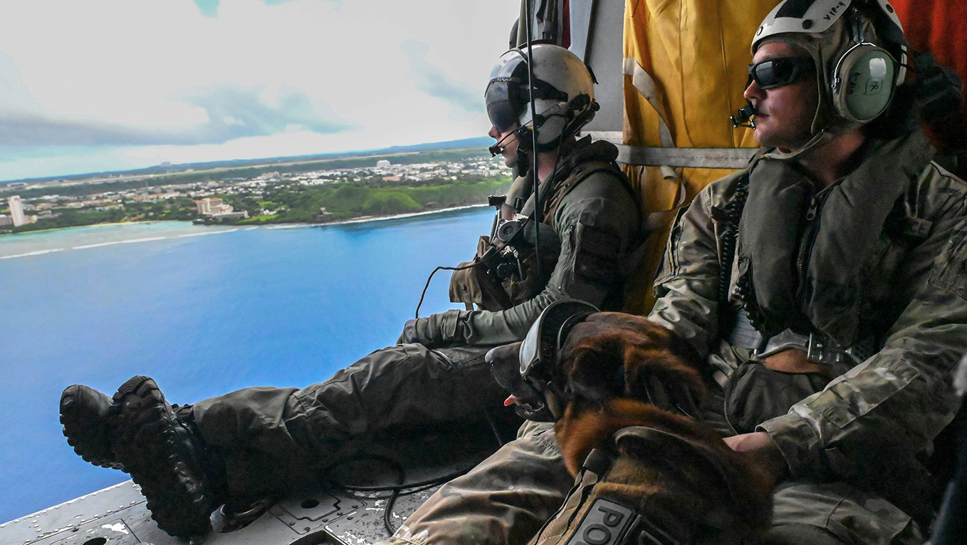 two airmen onboard an aircraft looking out